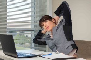 The image of business woman doing exercise at the office