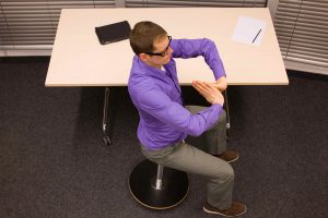 male office worker,exercising during short break in work at his desk in office